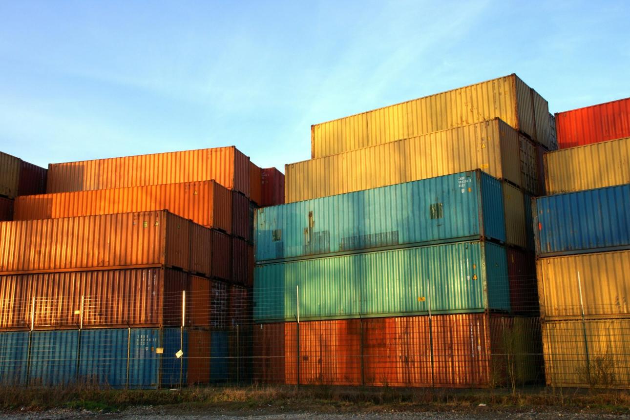 Colorful stacked shipping containers at a sunset-lit outdoor industrial site.
